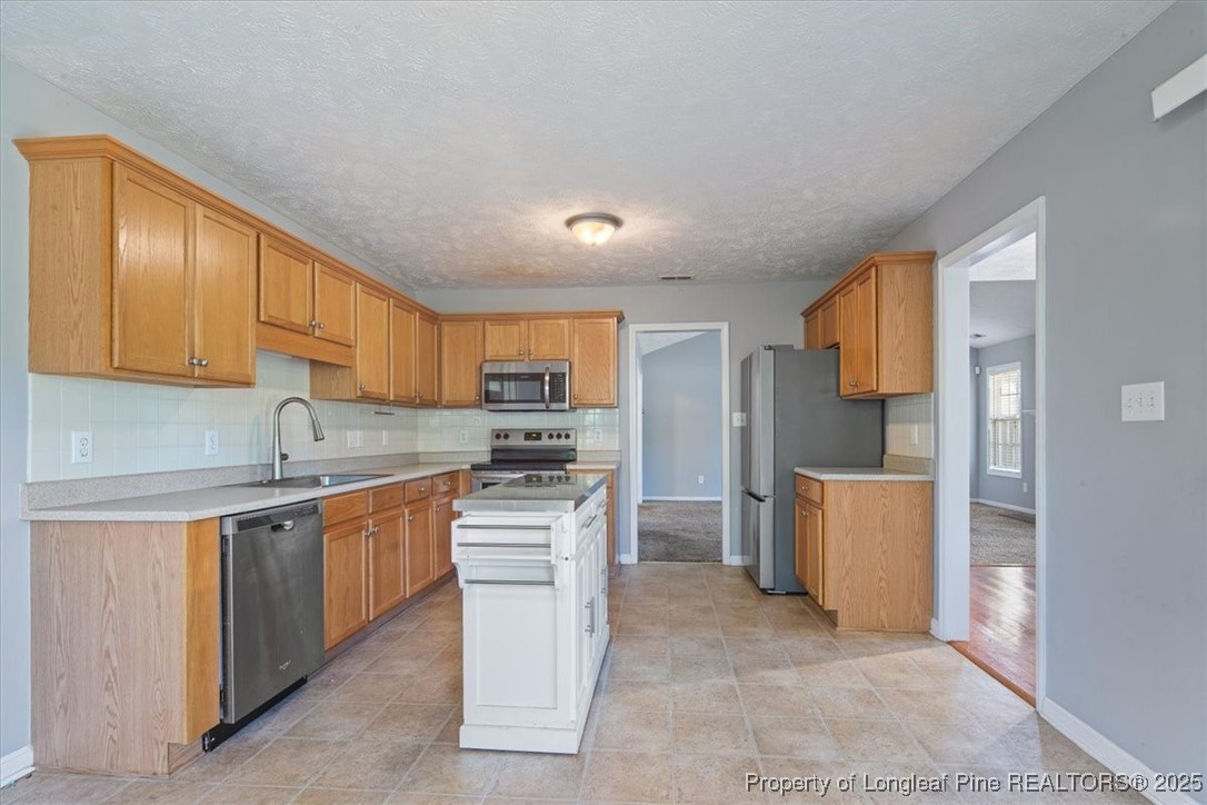 103 Beaumont Court Raeford, NC 28376 - Photo 23 of 50 a kitchen with stainless steel appliances a sink a stove a refrigerator cabinets and a window