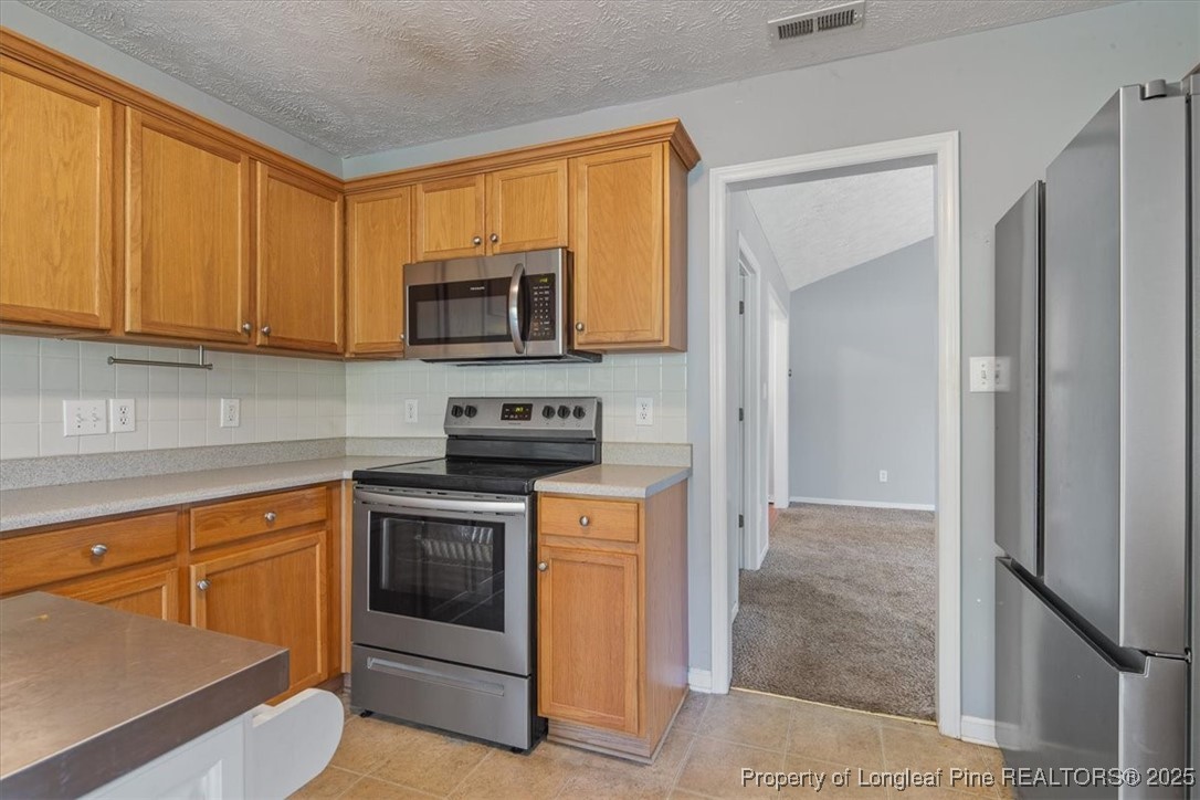 103 Beaumont Court Raeford, NC 28376 - Photo 25 of 50 a kitchen with stainless steel appliances granite countertop a stove microwave and refrigerator