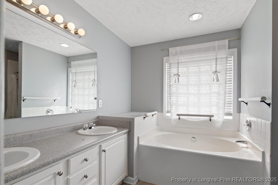 103 Beaumont Court Raeford, NC 28376 - Photo 31 of 50 a bathroom with a sink double vanity granite tub and a mirror