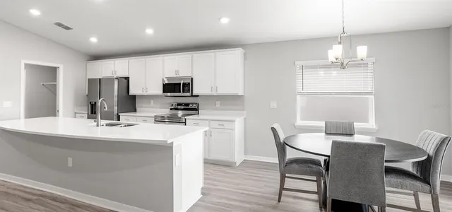 a kitchen with kitchen island a dining table chairs stainless steel appliances and cabinets