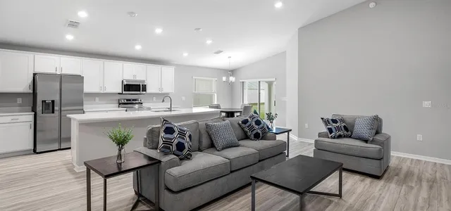 a living room with stainless steel appliances furniture and a view of kitchen