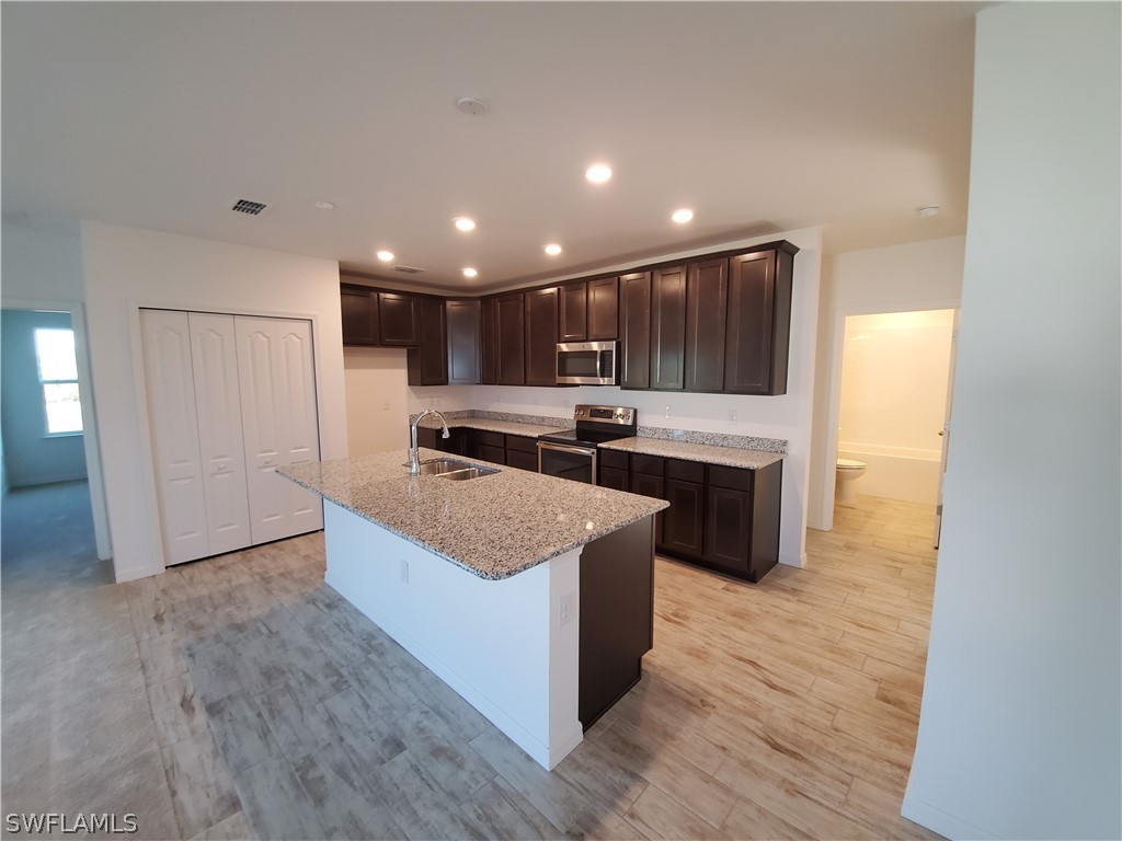 3916 Sunset Road Lehigh Acres, FL 33971 - Photo 3 of 11 a large kitchen with stainless steel appliances granite countertop a large counter top and wooden floors