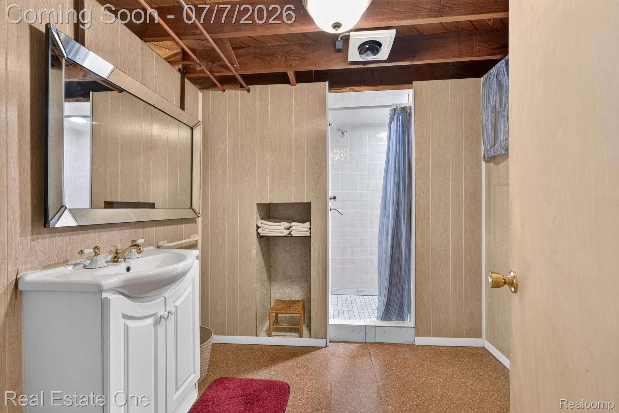 24749 Munson Street Taylor, MI 48180 - Photo 20 of 28 Bathroom featuring a single vanity with a white basin and brass-finish faucet, a framed mirror, and a shower with white tile surround