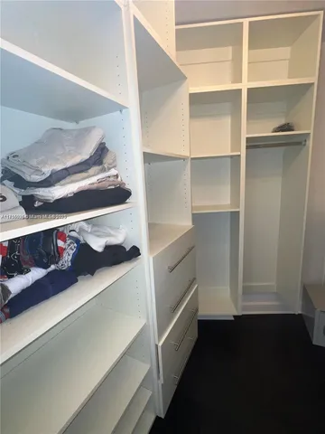 a walk in closet with wooden floor