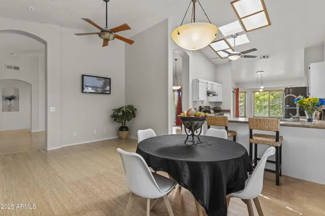 a kitchen with stainless steel appliances granite countertop a stove a refrigerator a sink a dining table and chairs with wooden floor