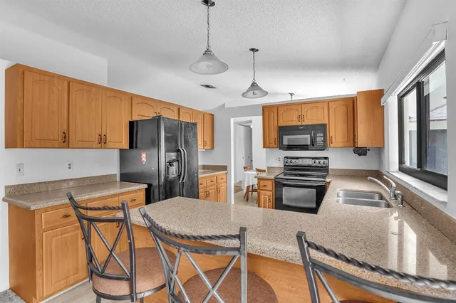 a kitchen with stainless steel appliances granite countertop a refrigerator a stove top oven a sink dishwasher and white cabinets with wooden floor