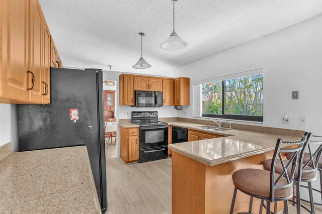 a kitchen with stainless steel appliances granite countertop a refrigerator a stove a sink a dining table and chairs with wooden floor