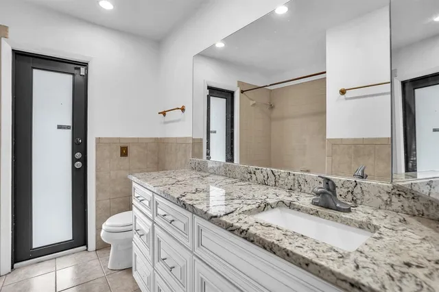 a bathroom with a granite countertop sink a toilet and shower