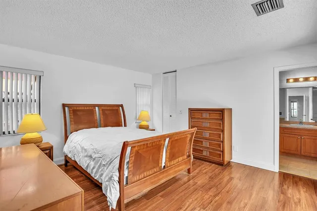 a bedroom with a bed and dresser with wooden floor
