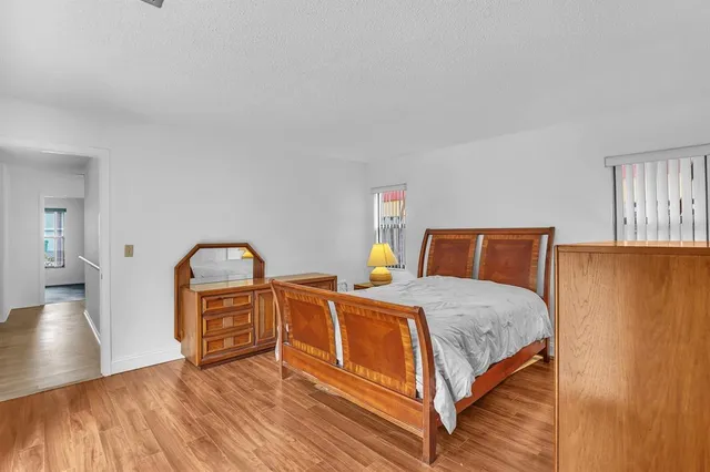 a bedroom with a bed and dresser with wooden floor