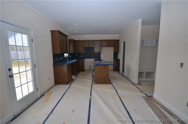 a living room with stainless steel appliances furniture a large window and a kitchen view