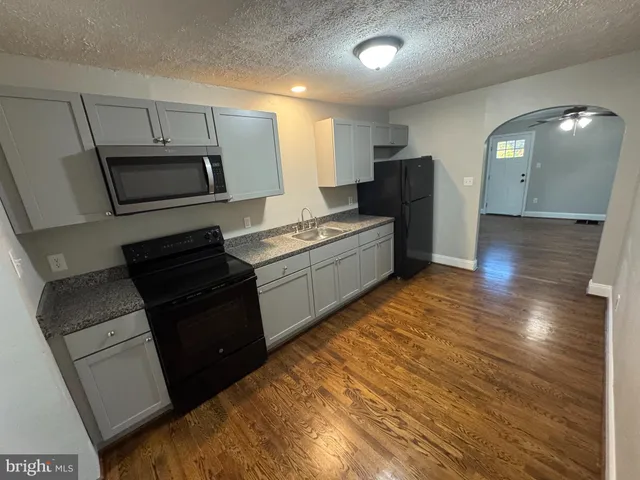 a kitchen with granite countertop a refrigerator stove and microwave