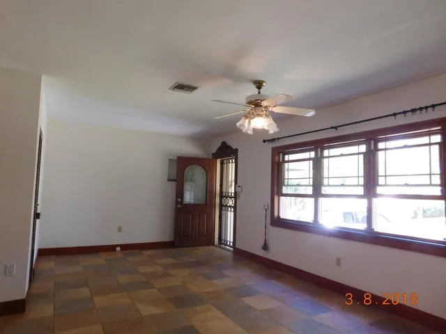 a view of an empty room with window and chandelier fan