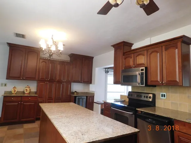 a kitchen with kitchen island granite countertop a stove top oven a sink a counter space and cabinets