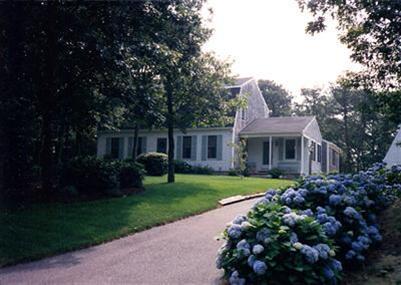 a front view of a house with a garden and trees