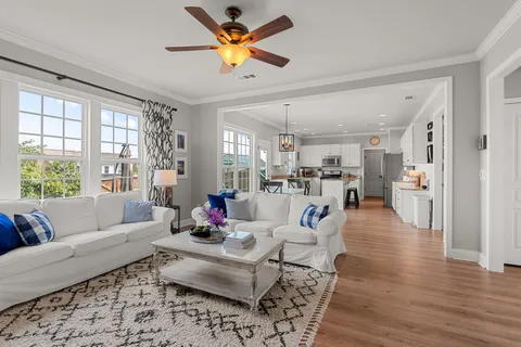 a living room with furniture kitchen view and a large window