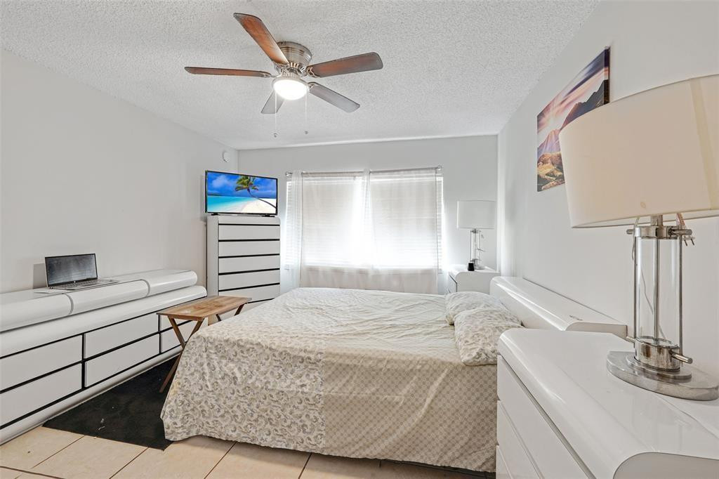 2710 Riverside Drive, Unit 106A Coral Springs, FL 33065 - Photo 5 of 8 a bedroom with a bed and a chandelier