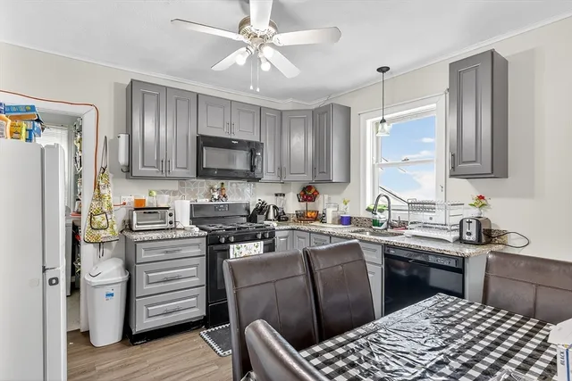 a kitchen with stainless steel appliances a stove a sink dishwasher a refrigerator with a dining table and chairs