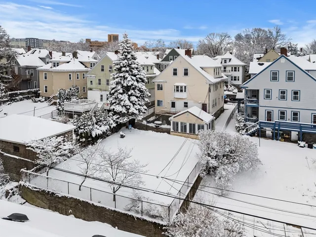 a view of a white building among the road and covered with snow in the background