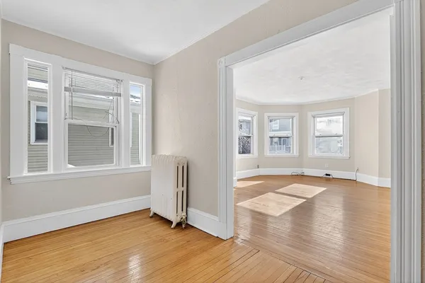 an empty room with wooden floor and windows
