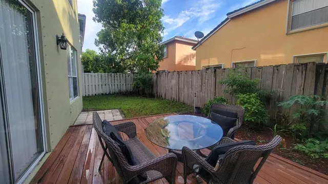 a view of a patio with table and chairs with wooden floor and fence