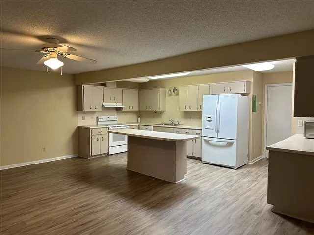 a large kitchen with a center island wooden floor stainless steel appliances and cabinets