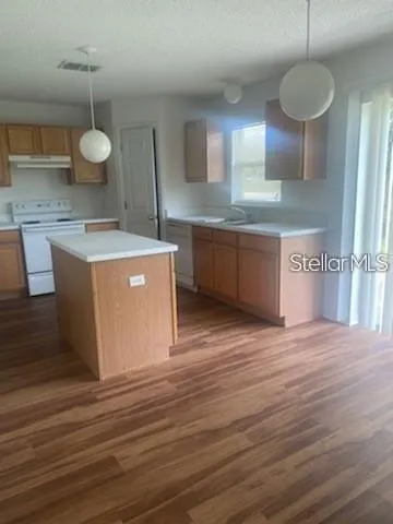 a kitchen with stainless steel appliances granite countertop a wooden cabinets and a wooden floor