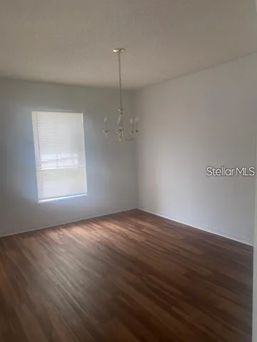 an empty room with wooden floor cabinet and windows