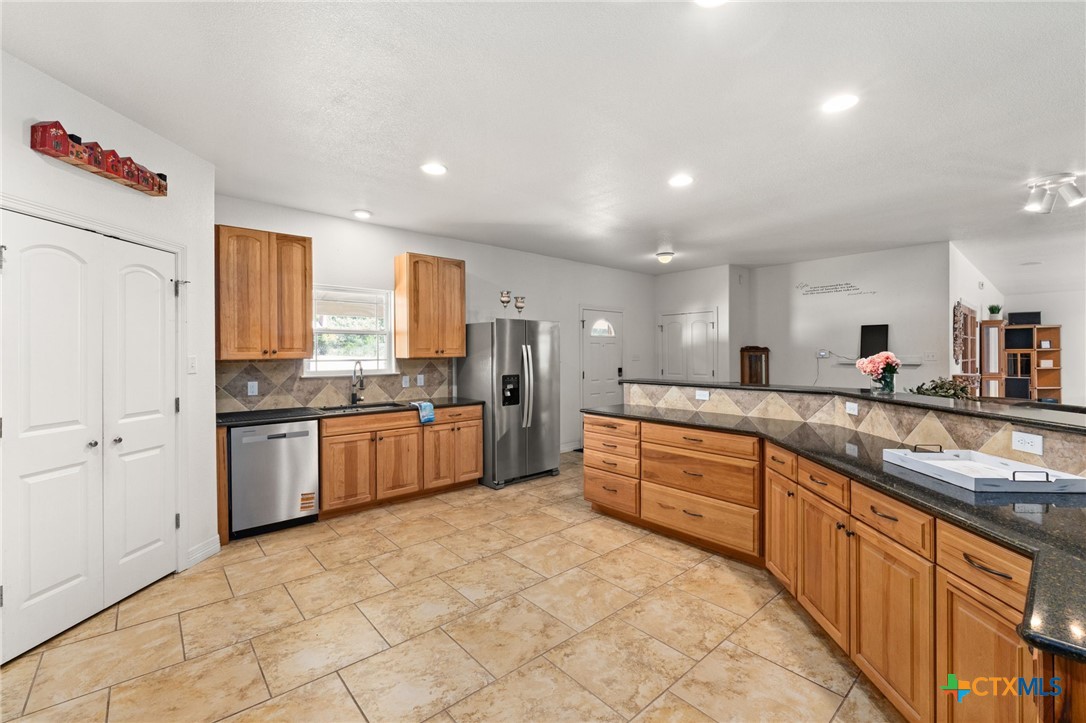 13061 Oakalla Road Killeen, TX 76549 - Photo 10 of 33 a large kitchen with kitchen island granite countertop a stove a sink dishwasher a refrigerator and white cabinets with wooden floor
