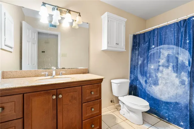 a bathroom with a granite countertop sink a toilet and a mirror