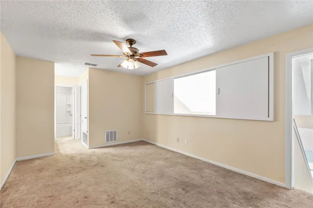 an empty room with windows and fan