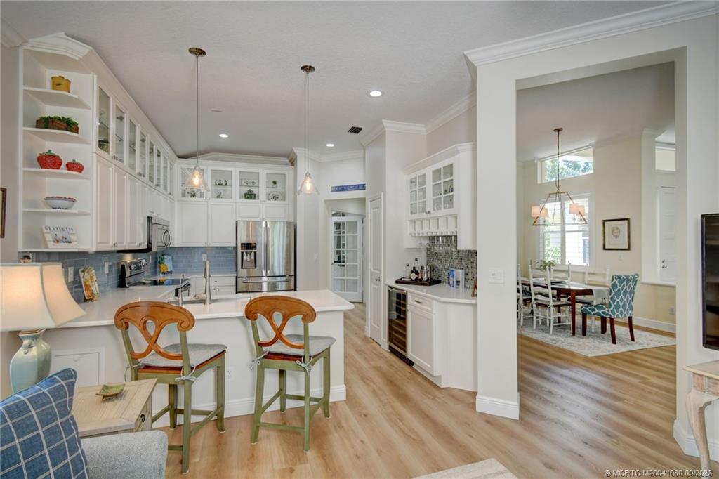 3531 Southeast Cambridge Drive Stuart, FL 34997 - Photo 16 of 44 a open kitchen with stainless steel appliances granite countertop a stove top oven a dining table and chairs with wooden floor