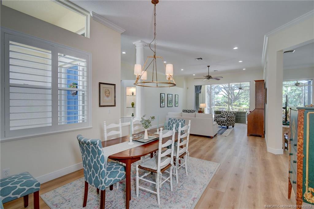 3531 Southeast Cambridge Drive Stuart, FL 34997 - Photo 10 of 44 a dining room with wooden floor a chandelier a wooden table and chairs