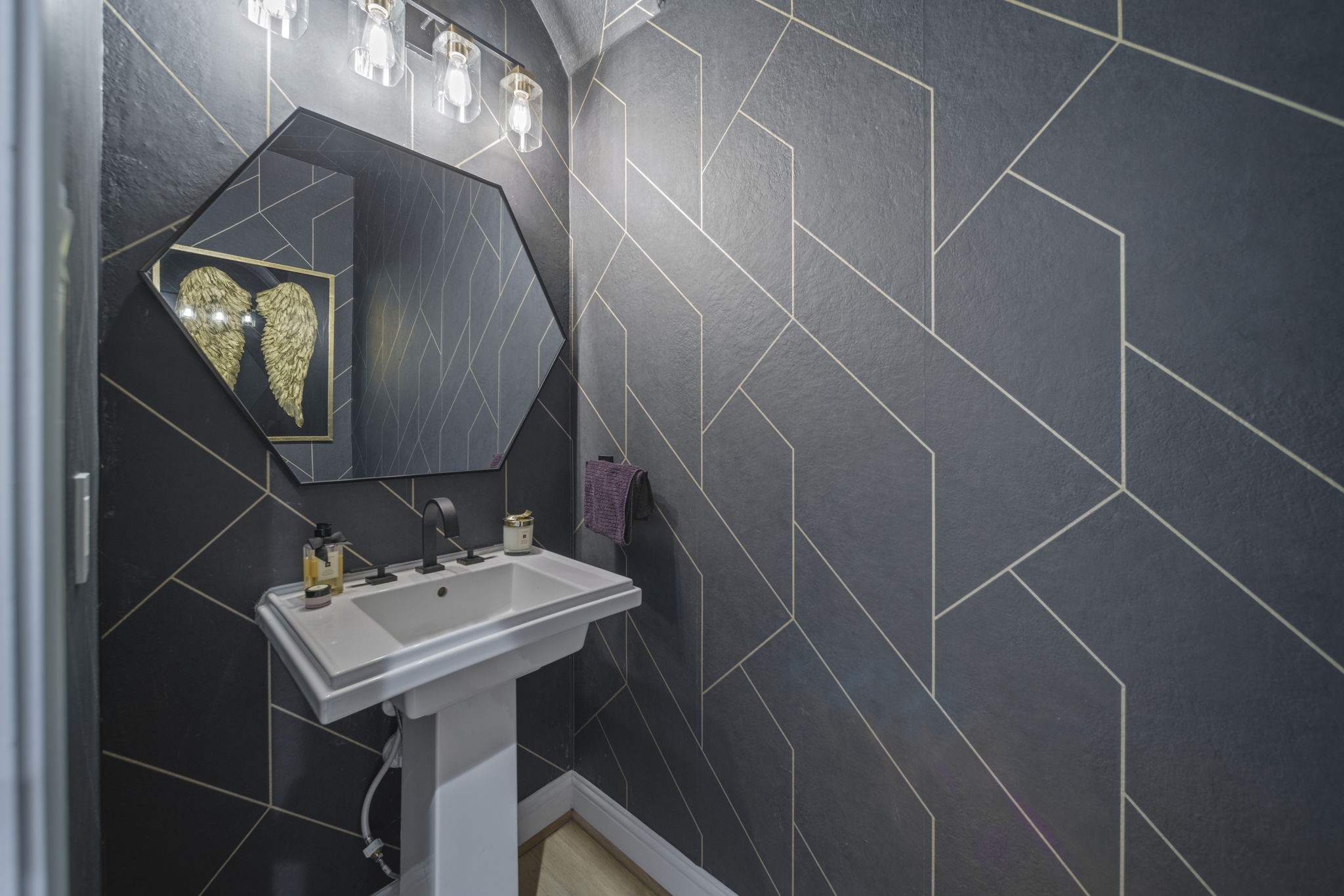 15 Inland Prairie Drive Tomball, TX 77375 - Photo 11 of 46 This powder room featuring a modern geometric wallpaper with gold accents. It includes a sleek pedestal sink, a unique mirror, and contemporary lighting.