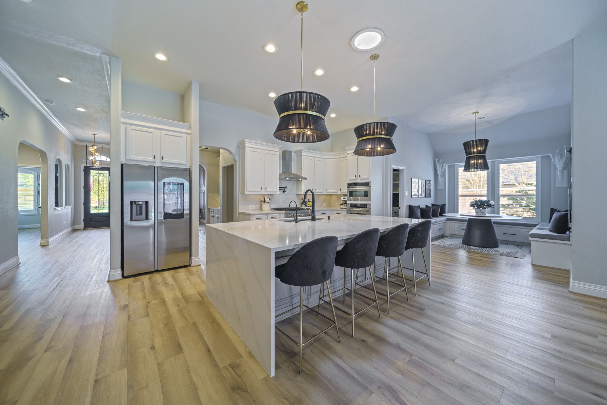 15 Inland Prairie Drive Tomball, TX 77375 - Photo 18 of 46 This modern kitchen features a spacious open layout with sleek white cabinetry, a large waterfall island with bar seating, stainless steel appliances, and elegant pendant lighting. The adjacent bright dining nook offers built in seating and ample natural light.