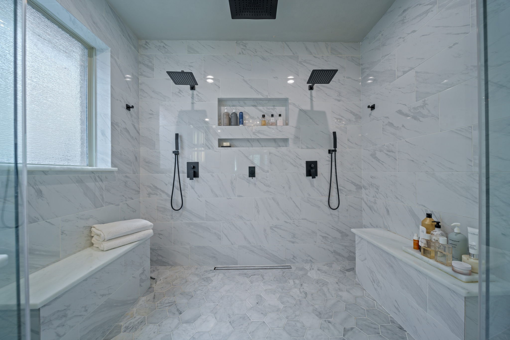 15 Inland Prairie Drive Tomball, TX 77375 - Photo 38 of 46 The sleek, large shower features black fixtures and rainfall showerheads. The bath is elegantly finished with marble-style tiles, built-in shelving, and benches for added convenience.