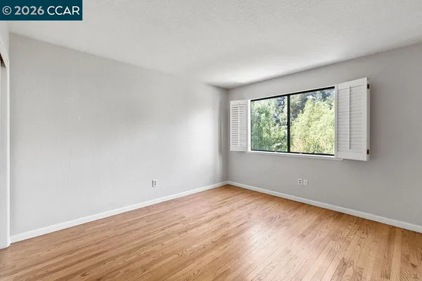 an empty room with wooden floor and windows