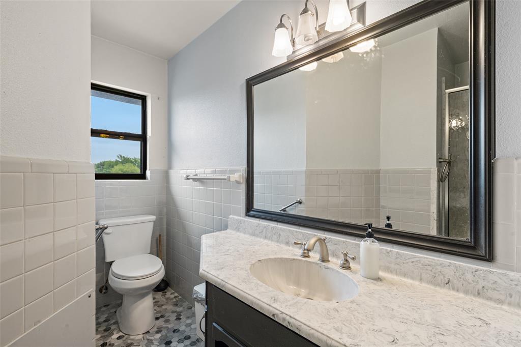 608 West Spring Street West, TX 76691 - Photo 13 of 27 a bathroom with a granite countertop toilet a sink and a mirror