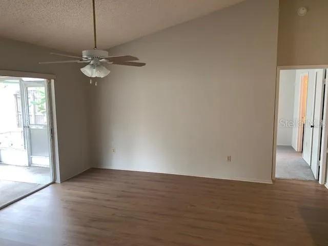 an empty room with wooden floor fan and windows