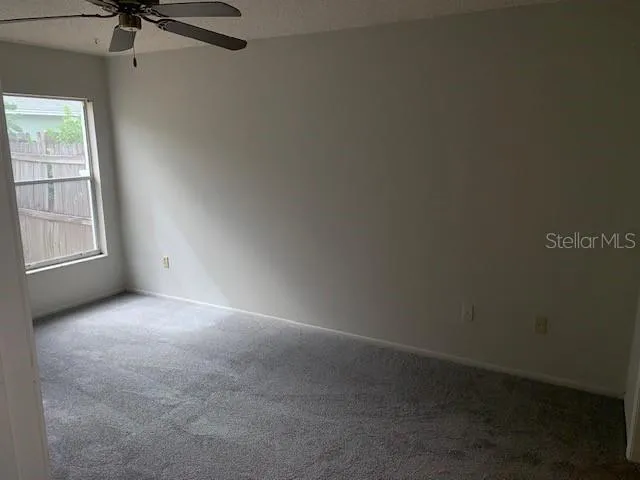 an empty room with windows and fan