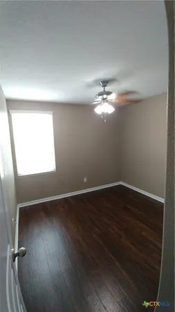 a view of a room with wooden floor and a ceiling fan