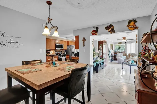 a view of a dining room and livingroom with furniture wooden floor a rug a painting and a chandelier