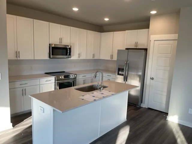 a kitchen with stainless steel appliances a refrigerator a stove a sink and white cabinets