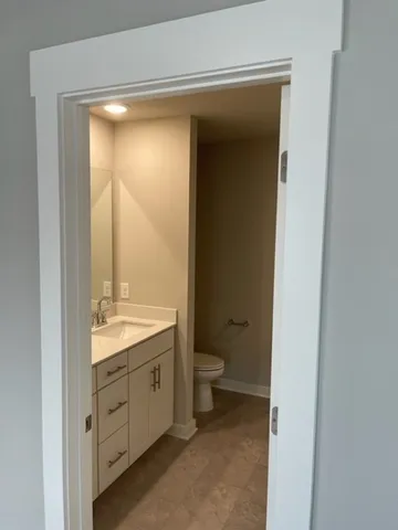 a bathroom with a granite countertop sink toilet and mirror