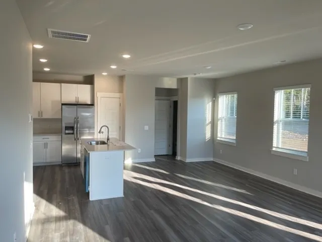 a kitchen with stainless steel appliances granite countertop a stove a sink dishwasher and a refrigerator with wooden floor