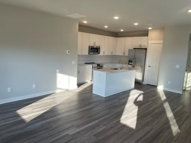 a kitchen with stainless steel appliances granite countertop a stove top oven a sink dishwasher and a refrigerator with wooden floor