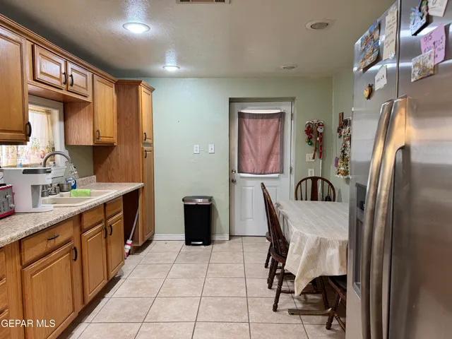 a kitchen with stainless steel appliances granite countertop a refrigerator a sink a stove top oven a dining table and chairs with wooden floor
