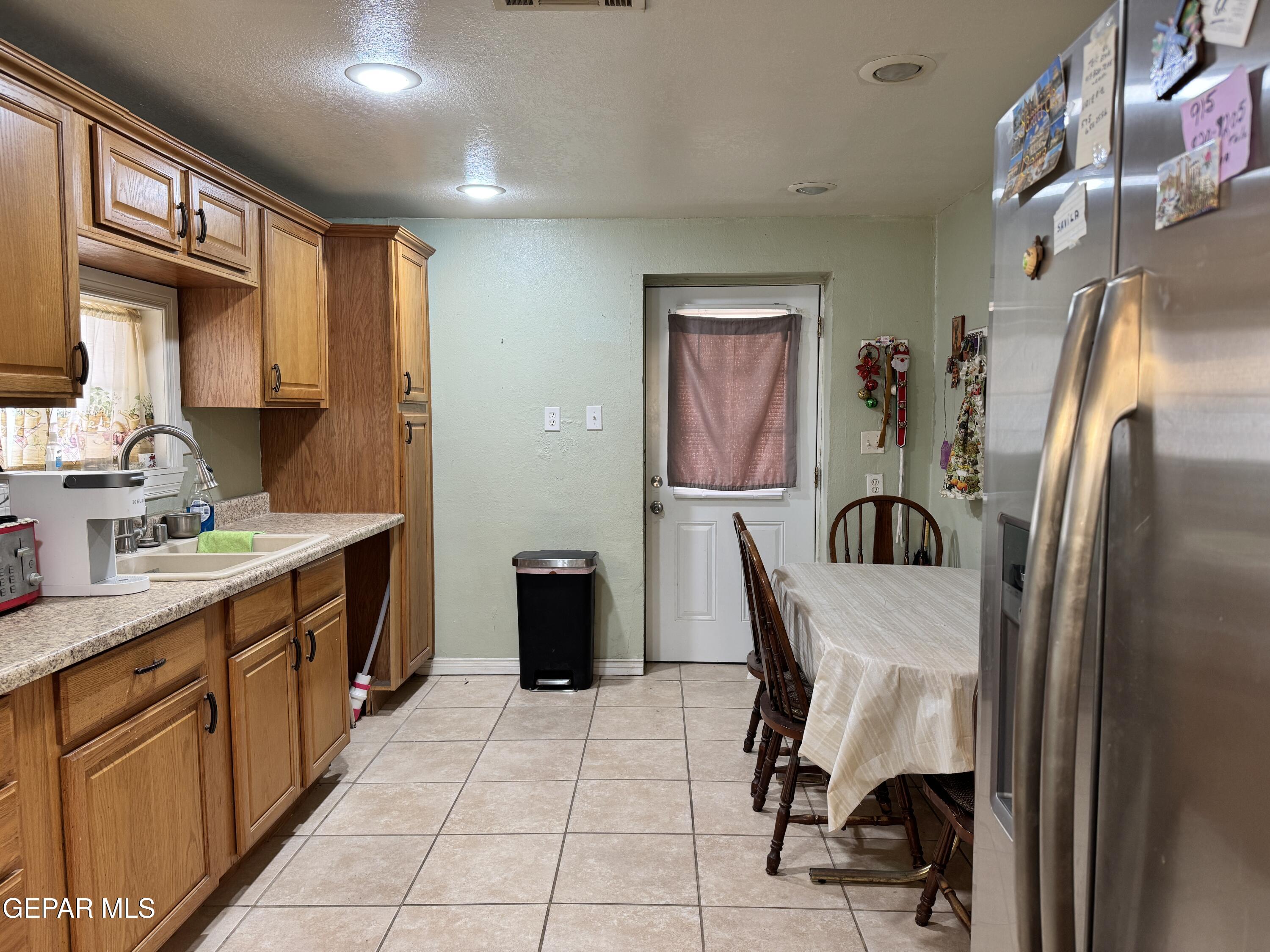 316 St Anthony Street Anthony, NM 88021 - Photo 8 of 29 a kitchen with stainless steel appliances granite countertop a refrigerator a sink a stove top oven a dining table and chairs with wooden floor