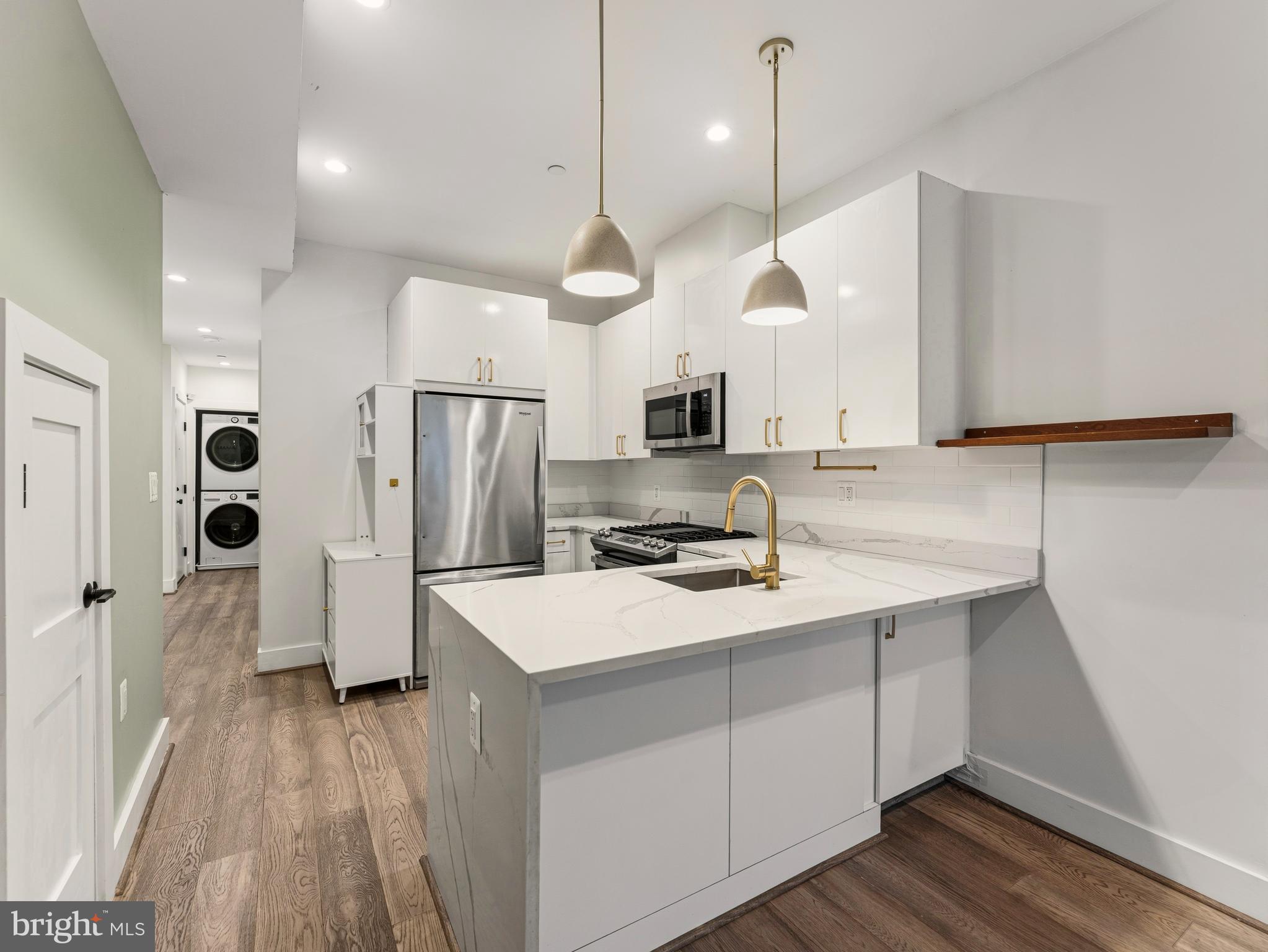 1120 Penn Street Northeast, Unit 2 Washington, DC 20002 - Photo 4 of 14 a kitchen with stainless steel appliances a stove a sink a refrigerator a center island with wooden floor and cabinets