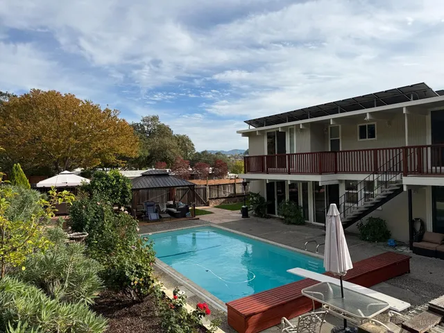an aerial view of a house with swimming pool big yard and large trees